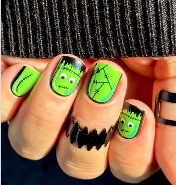 a hand with green and black painted nails